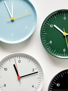 four different clocks are on the wall and one is black, white, and green