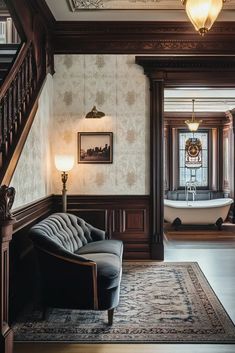 a living room with a couch, chair and chandelier next to a staircase