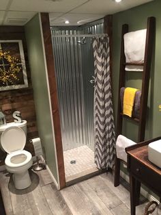 a bathroom with a toilet, sink and shower stall in the corner next to a wooden ladder