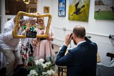 a man taking a picture of a woman in a wedding dress holding a framed photo