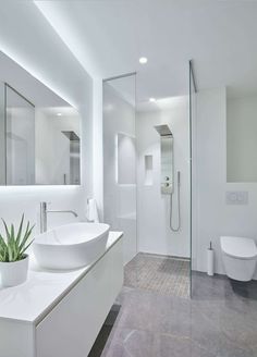 a white bathroom with two sinks and a large mirror on the wall next to it