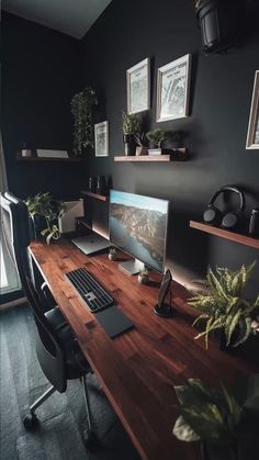 a desk with a computer on it in front of a window and some potted plants