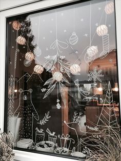 a window with christmas decorations drawn on it and lights hanging from the windowsills