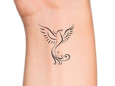 a small tattoo on the wrist of a woman with a bird flying above her arm