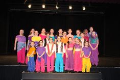 a group of young people standing on top of a stage next to eachother