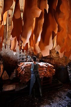 a man standing in front of a pile of wood with lots of large pieces hanging from the ceiling