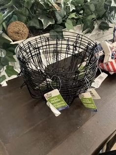 a wire basket sitting on top of a wooden table next to green plants and other items