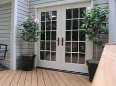 two potted plants sitting on top of a wooden deck next to a patio door