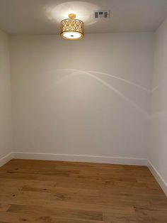 an empty room with hard wood floors and white walls is seen in this image from the corner