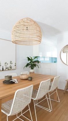 a dining room table with white chairs and an oval light fixture hanging over it's head