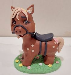 a toy horse with a saddle on it's head and nose sitting on a green base