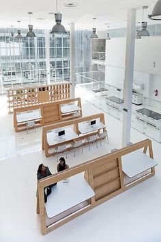 two people are sitting on benches in the middle of a large room with tables and chairs