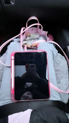 a pink tablet sitting on top of a blanket in the back seat of a car