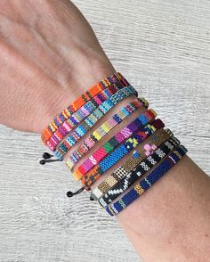 a woman's hand holding several bracelets on her wrist, all in different colors