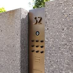 a metal plaque on the side of a stone wall with numbers and holes in it