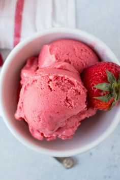 three scoops of strawberry ice cream in a white bowl