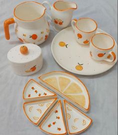 an assortment of oranges and white dishes on a table