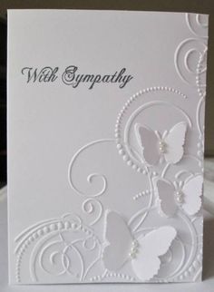 a white greeting card with butterflies and swirls in the middle, on a table