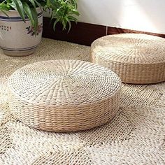 two round woven baskets sitting on top of a rug next to a potted plant