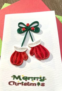 a christmas card with two red mittens on top of it and the words merry christmas is written in green