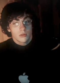 a young man wearing glasses is looking at his computer screen with an apple logo on it