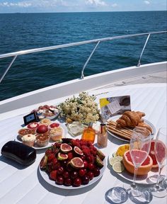 a table full of food and drinks on a boat in the ocean with blue water