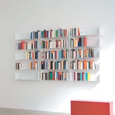 a bookshelf filled with lots of books next to a red box on the floor