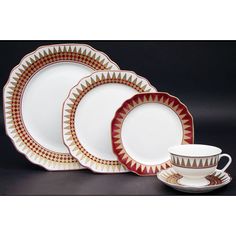 a set of four dinner plates with matching cups and saucers in red, white and gold