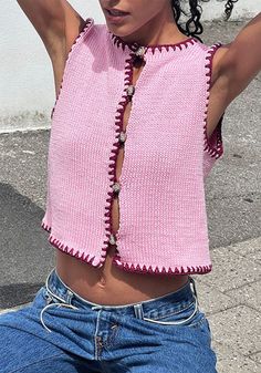 a woman in jeans and a pink top is posing for the camera with her arms behind her head