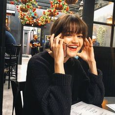 a woman sitting at a table talking on her cell phone