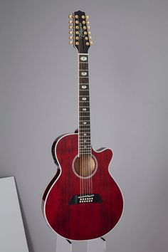 a red acoustic guitar on display in a room with gray walls and white flooring