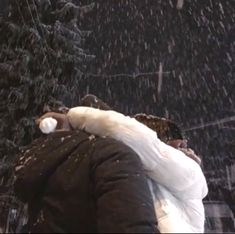 a man standing in the snow with his arms wrapped around him and holding an umbrella