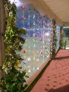 an outdoor area with paper cranes hanging from the ceiling and plants growing on the wall