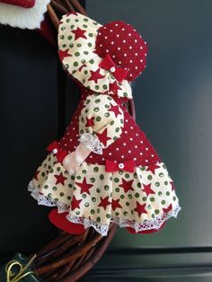 a red and white teddy bear sitting on top of a wooden door handle next to a wreath