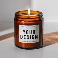 a candle that is sitting on a table next to a window with the words your design printed on it