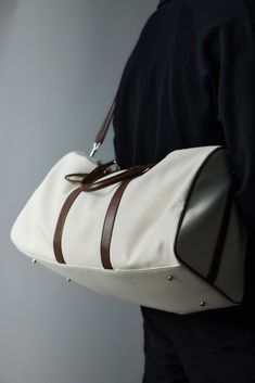 The Modern Canvas Duffle Bag effortlessly blends contemporary style with superior craftsmanship, making it a must-have for both travel and everyday use. Constructed from premium cotton canvas, this bag features PU leather accents that add a touch of sophistication and durability. The base of the bag is reinforced with four rivets, providing extra protection against wear and tear and extending its lifespan. Designed for versatility, it includes a detachable strap, allowing you to carry it as a cr Functional White Shoulder Bag With Luggage Sleeve, White Rectangular Weekender Bag For Everyday, Elegant Canvas Travel Bag With Leather Handles, Everyday Duffle Bag With Leather Trim, White Functional Duffle Bag For Weekend Trips, Functional White Duffle Bag For Everyday Use, Functional White Duffle Bag For Weekend Trips, Modern Weekender Bag For Daily Use, Everyday Large Capacity Cream Duffle Bag