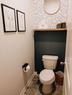 a white toilet sitting in a bathroom next to a wall with pictures hanging on it