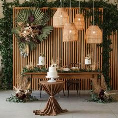 a table topped with a white cake next to a wooden wall covered in greenery