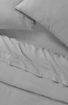 an unmade bed with two pillows and one pillow on top of the covers is shown in black and white