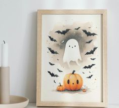 a painting of a ghost and two pumpkins on a shelf next to a candle