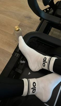 the legs of a person in white socks and black pants are resting on an exercise machine