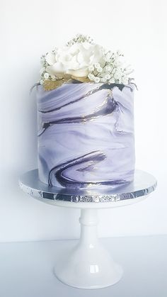 there is a cake with purple icing and white flowers on the top of it