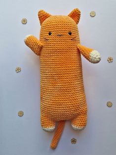 an orange crocheted stuffed animal laying on top of a white surface with tiny gold dots around it