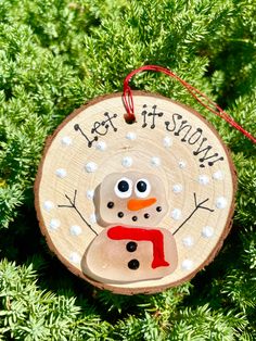 a wooden ornament with a snowman painted on it's face and the words let it snow