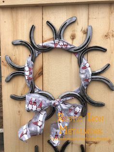 a wreath made out of horseshoes with bows hanging on the side of a wooden fence