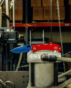 a red and blue knife is on top of a metal container in a factory area