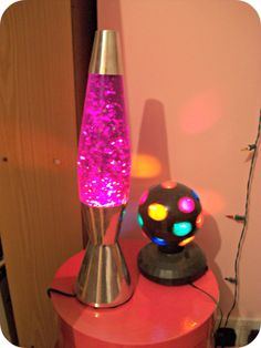 a lamp that is sitting on top of a red table next to a pink wall