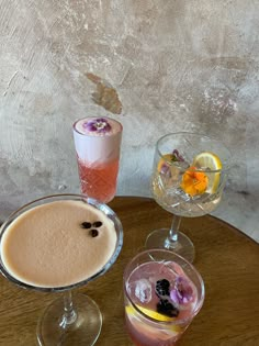 three different types of drinks sitting on a table next to each other with flowers in them