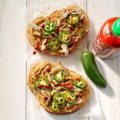 two chicken sandwiches with peppers, jalapenos and ketchup on top