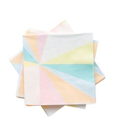 three napkins on top of each other with different colors and shapes in the background